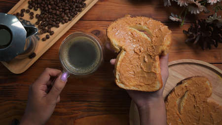 Top view retro camera, coffee cup and toast bread with peanut butter on wooden table.の写真素材