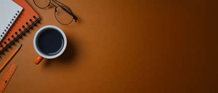A coffee cup, glasses and notebook on orange leather with cop space.の写真素材