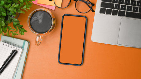 Top view mock up smart phone, coffee cup and computer laptop on orange background.の写真素材