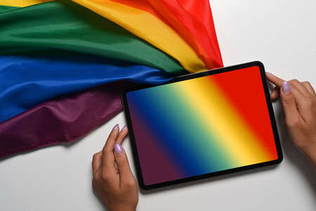 Above view female holding digital tablet with rainbow flag on white background.の写真素材