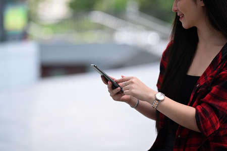 Happy woman using smart phone and standing on a city street.の写真素材