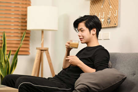 Casual Asian man lying on sofa and surfing internet with computer tablet.の写真素材