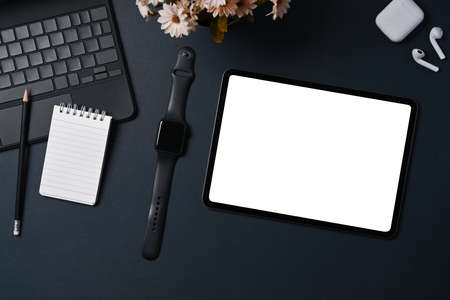 Top view, digital tablet with blank screen and smart watch on black leather.