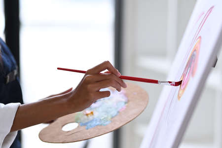 Close up view artist woman holding palette and painting picture in art studio.の写真素材