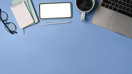 Above view smart phone, laptop computer, notebook and coffee cup on blue background.の写真素材