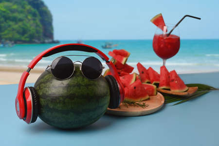 Sliced watermelon and watermelon smoothie on table with beautiful summer beach in background.の写真素材