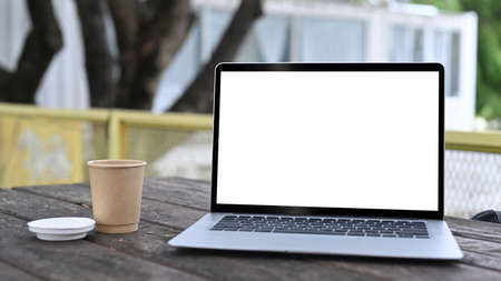 Mock up portable laptop and coffee cup on wooden table outdoors.の写真素材
