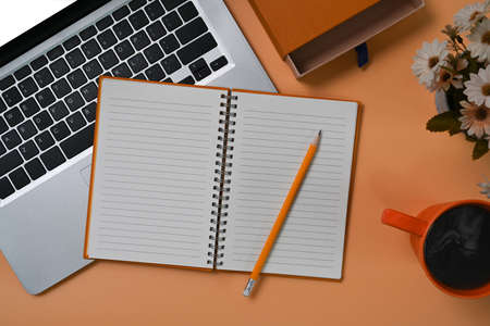 Empty notebook, computer laptop and coffee cup on beige background.の写真素材