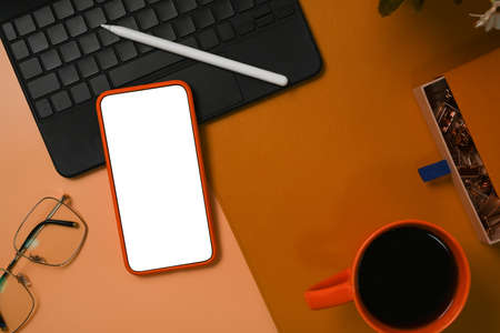 Mobile phone with blank screen, laptop computer, glasses and coffee cup on stylish workspace.の写真素材