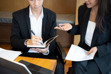 Disabled young man on wheelchair working in modern office with his colleague.