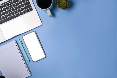 Top view mobile phone, laptop computer, notebook and coffee cup on blue background.の写真素材
