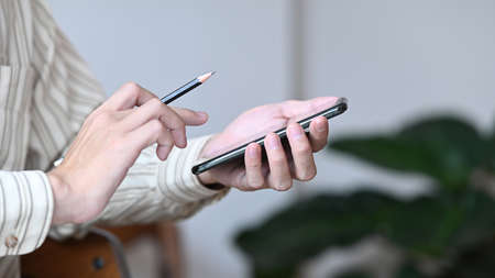 Cropped shot young man sitting in cafe and using smart phone.の写真素材