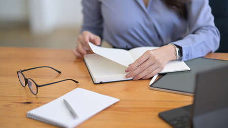 Businesswoman reading information on notebook and working with digital tablet.の写真素材