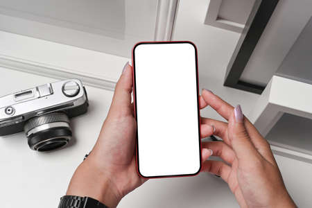 Female photographer holding smart phone with blank screen.