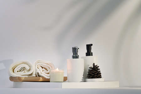 Burning aromatic candle, towels and shampoo bottles on white table. Spa accessories.の写真素材