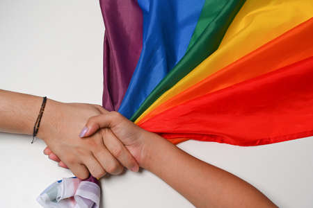 Two women LGBT lesbian hands are holding each other over LGBT pride flag.の写真素材