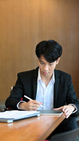 Asian businessman holding stylus pen and working on digital tablet.の写真素材