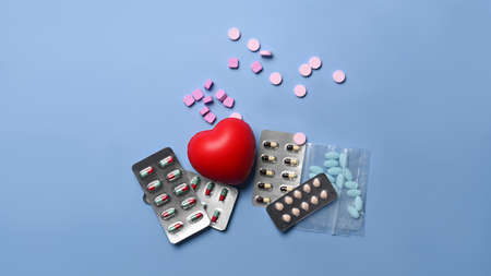 Colorful medical pills, capsules and red heart on blue background.の写真素材