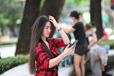 Young Asian woman sitting outdoor and using smart phone.の写真素材