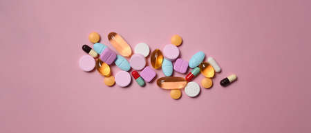 Pharmaceutical tablets and capsules over pink background.の写真素材