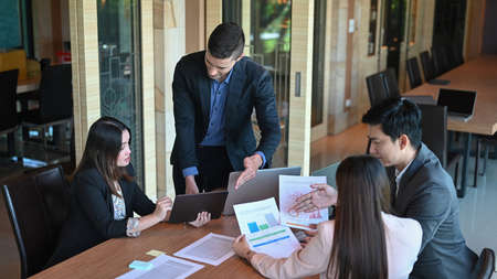 Smiling businessman holding financial documents and explaining information to his colleagues.の写真素材