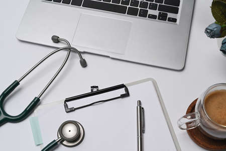Above view doctor workspace with laptop computer, clipboard, stethoscope and coffee cup.の写真素材