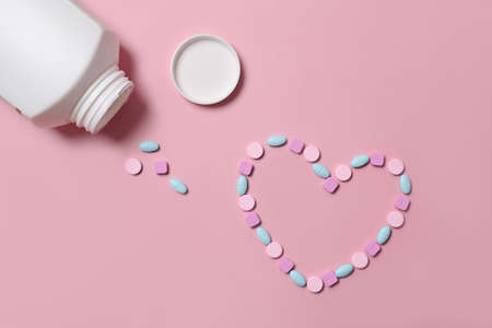 Man holding medical pills and pill bottle on pink background.の写真素材