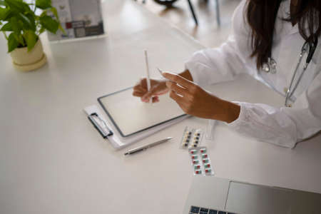 Female doctor holding stylus pen and writing medical informations on digital tablet.の写真素材