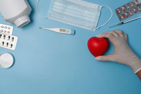Female holding red heart on blue background. Cardiology and insurance concept.の写真素材