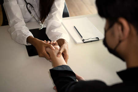 Doctor examining the patients pulse by hands in medical room.の写真素材