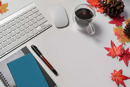 Top view cup of hot beverage, notebooks and autumn maple leaves on white background.の写真素材