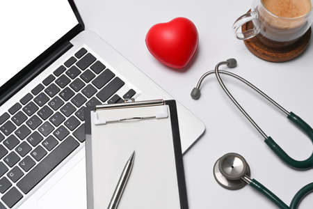 Red heart, empty clipboard, laptop computer and stethoscope on doctor workspace.の写真素材