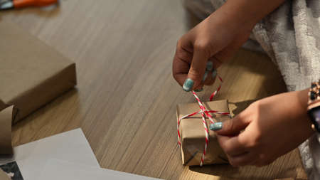 Close up view young woman wrapping Christmas gifts in living room.の写真素材