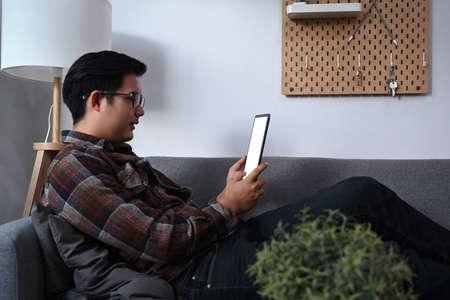 Peaceful man relaxing on couch and drinking coffee.の写真素材