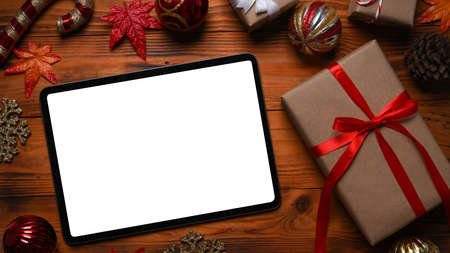 Digital tablet, gift boxes and Christmas ornaments on wooden background.の写真素材