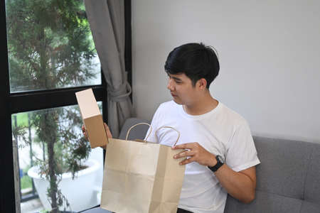 Handsome Asian man giving gift box and looking at camera.の写真素材