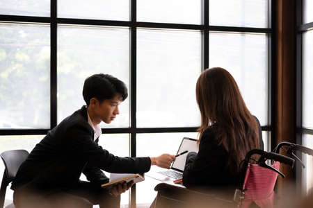 Businesswoman in wheelchair working in the office with her colleague.の写真素材