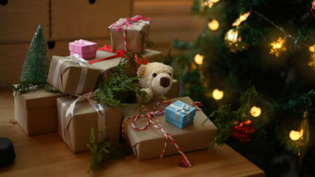 Christmas gift boxes on wooden table near the Christmas tree in living room.の写真素材