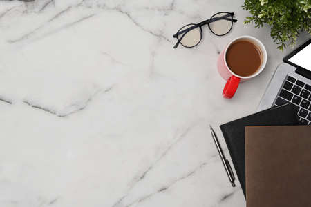 Top view laptop computer, notebook, coffee cup and glasses on marble table.の写真素材