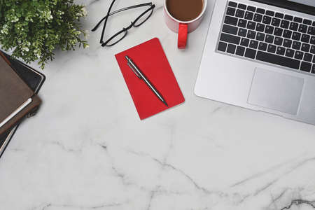 Top view laptop computer, notebook, coffee cup and glasses on marble table.の写真素材
