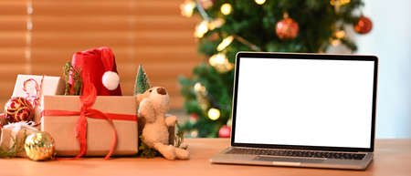 Digital tablet with blank display and Christmas presents on wooden table.の写真素材