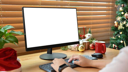 Mock up computer with white display, houseplant and Christmas gifts on wooden table.の写真素材