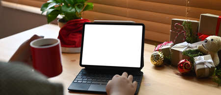 Close up view woman holding coffee cup and surfing internet or shopping online at Christmas time.の写真素材