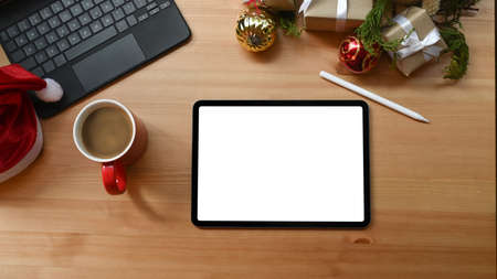 Digital tablet with blank display and Christmas presents on wooden table.の写真素材