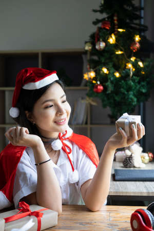 Smiling young asian woman in Santa hat holding Christmas gift box.の写真素材