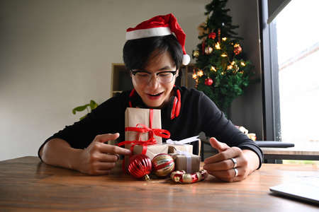 Happy man wearing Santa hat and holding Christmas presents.の写真素材