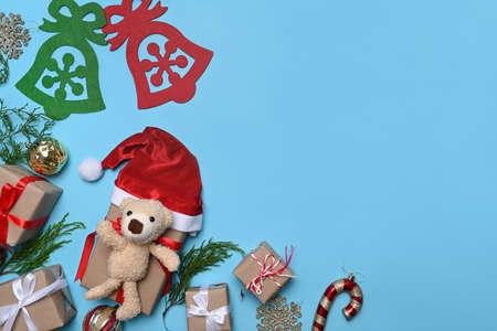 Teddy bear, pine tree branch , Christmas ornaments and gift boxes on blue background.の写真素材
