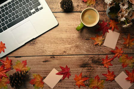 Notebook, Computer laptop, coffee cup and autumn maple leaves on wooden background.の写真素材
