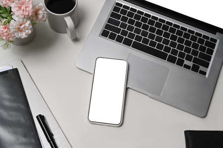 Computer laptop, notepad, coffee cup, glasses and maple leaves on white table.
