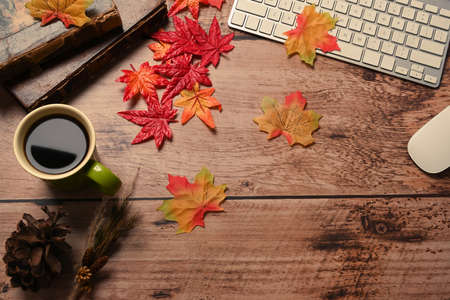 Coffee cup, vintage books, glasses and autumn maple leaves on wooden table.の写真素材